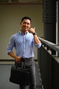 Portrait of young man standing against wall