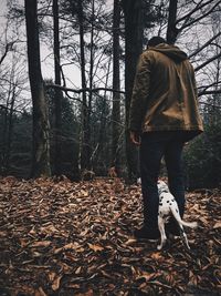 Man with dog walking in forest during winter