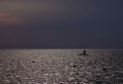 Silhouette man on sea against sky