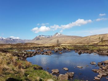 Scenic view of lake by mountains against blue sky