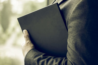 Midsection of businessman holding book