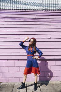 Full length portrait of woman standing against wall