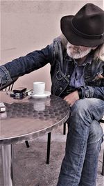 Midsection of man with coffee cup sitting on table