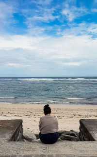 Rear view of man sitting on beach