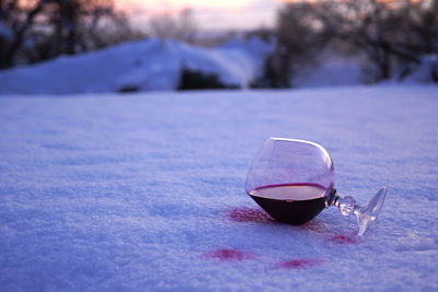 Close-up of red wine spilled on snow during sunset