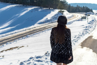 Rear view of woman standing on snow covered land