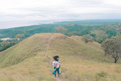 Rear view of woman standing on mountain against sky