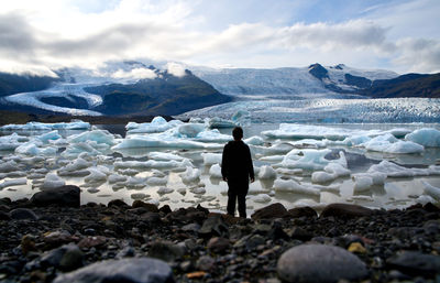 Rear view of man standing on snowcapped mountain