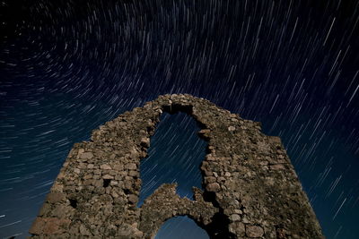 Low angle view of old stone wall against sky at night