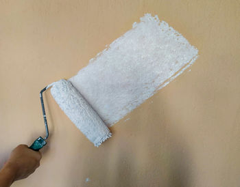 Close-up of hand holding ice cream against wall