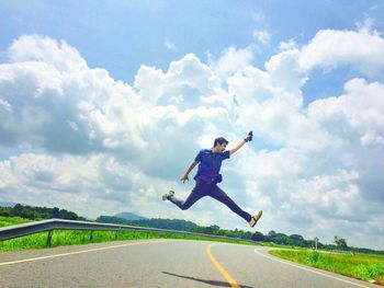 Man jumping on road against sky