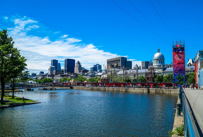 River by buildings against blue sky