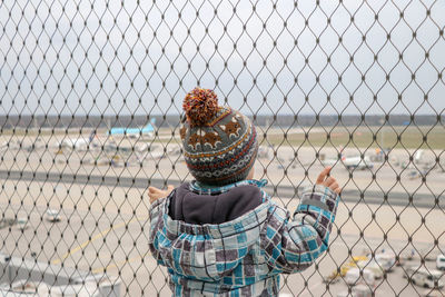 Rear view of a person holding chainlink fence