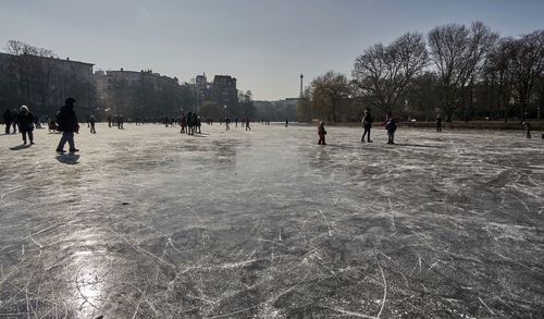 People on riverbank against sky