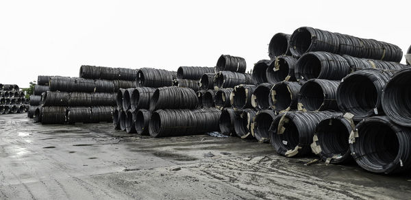 Stack of pipes on field against clear sky