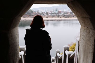 Rear view of woman standing by lake against sky