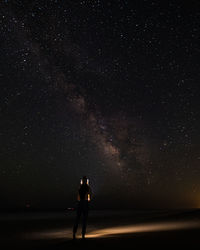 Silhouette person standing on field against sky at night