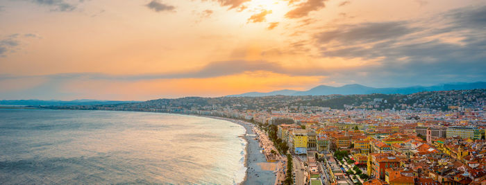 Aerial view of town by sea against sky during sunset