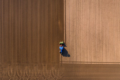 Shades of brown appear on a field that is plowed with a tractor and seen from a drone perspective