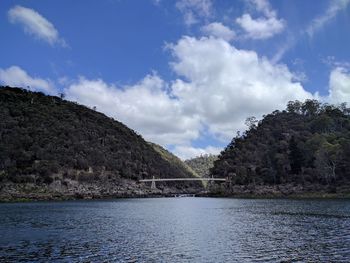 Scenic view of river by mountains against sky