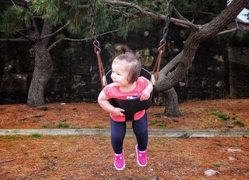 Portrait of happy girl standing against tree