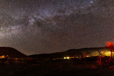 Scenic view of illuminated mountains against milky way at night