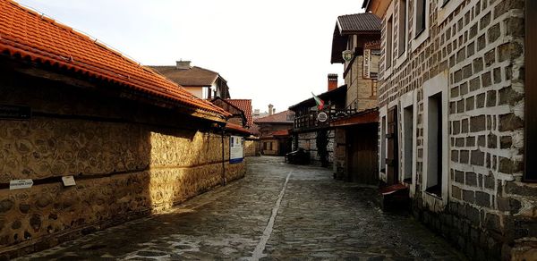 Walkway amidst buildings against sky