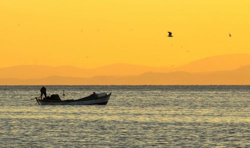 Boat sailing in sea at sunset