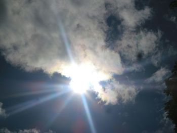 Low angle view of sun shining through clouds