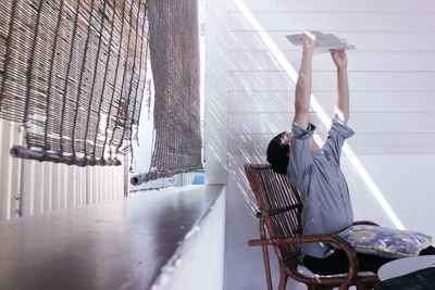 Man reading book at home by window