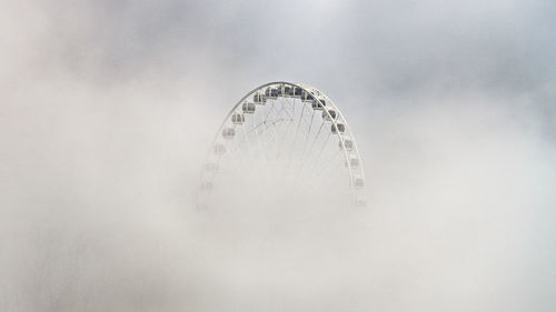 A ferris wheel appears through the fog in canada