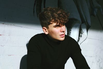 Portrait of young man standing against wall