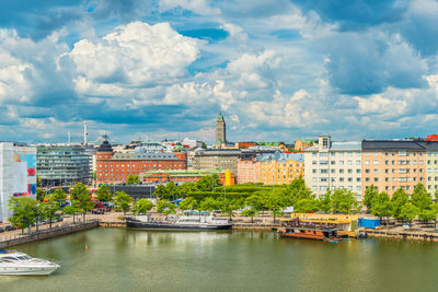 Buildings by river against cloudy sky