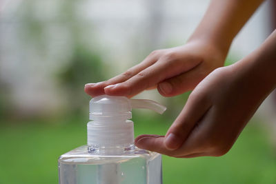 Close-up of person applying hand sanitizer outdoors