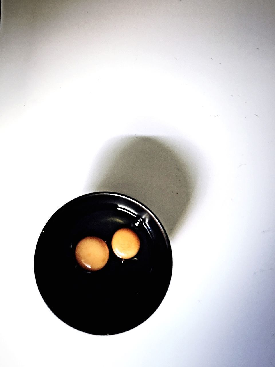 studio shot, white background, copy space, still life, indoors, single object, close-up, cut out, circle, directly above, no people, high angle view, table, two objects, simplicity, wall - building feature, geometric shape, black color, food and drink, overhead view