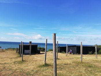 Wooden post on field against blue sky