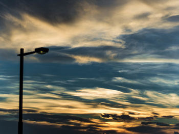 Low angle view of street light against dramatic sky