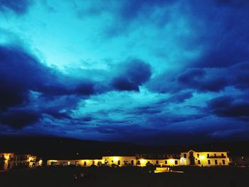 View of town against cloudy sky at night