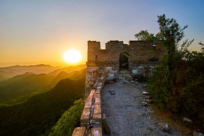 Broken brick wall on mountain against clear sky during sunrise