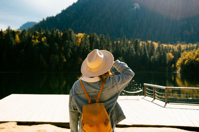 Rear view of man by lake against trees