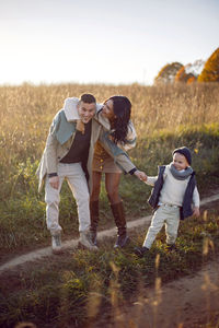 Stylish family with a boy child on a field in the dry grass in autumn