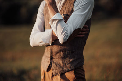 Midsection of man holding umbrella standing on field