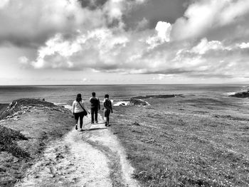 People hiking sandstone cliff against ocean background. monochrome.