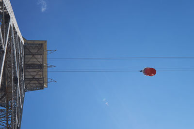 Low angle view of telephone pole against clear blue sky