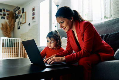 Young executive woman working from home while taking care of her young daughter