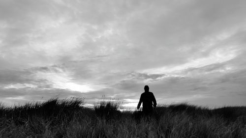 Rear view of silhouette man standing on field against sky