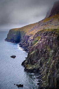 Scenic view of cliff by sea against sky