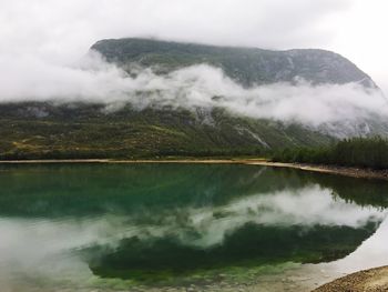 Scenic view of lake by mountains against sky