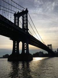 Low angle view of silhouette manhattan bridge over east river during sunset