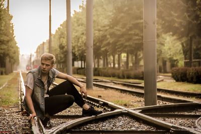 Young man sitting on railroad track